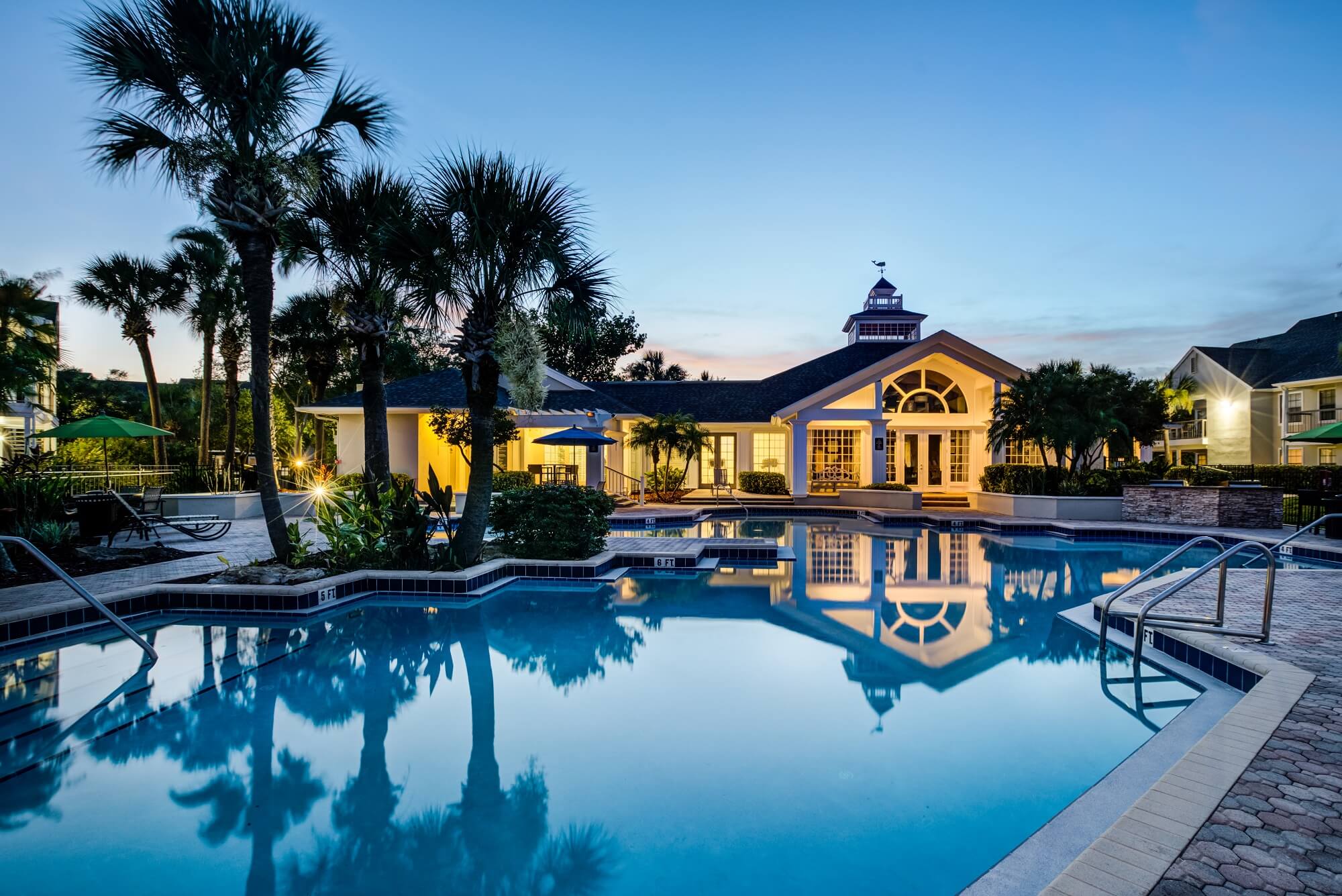 night time pool view with palm trees, lounge chairs, and view of clubhouse.