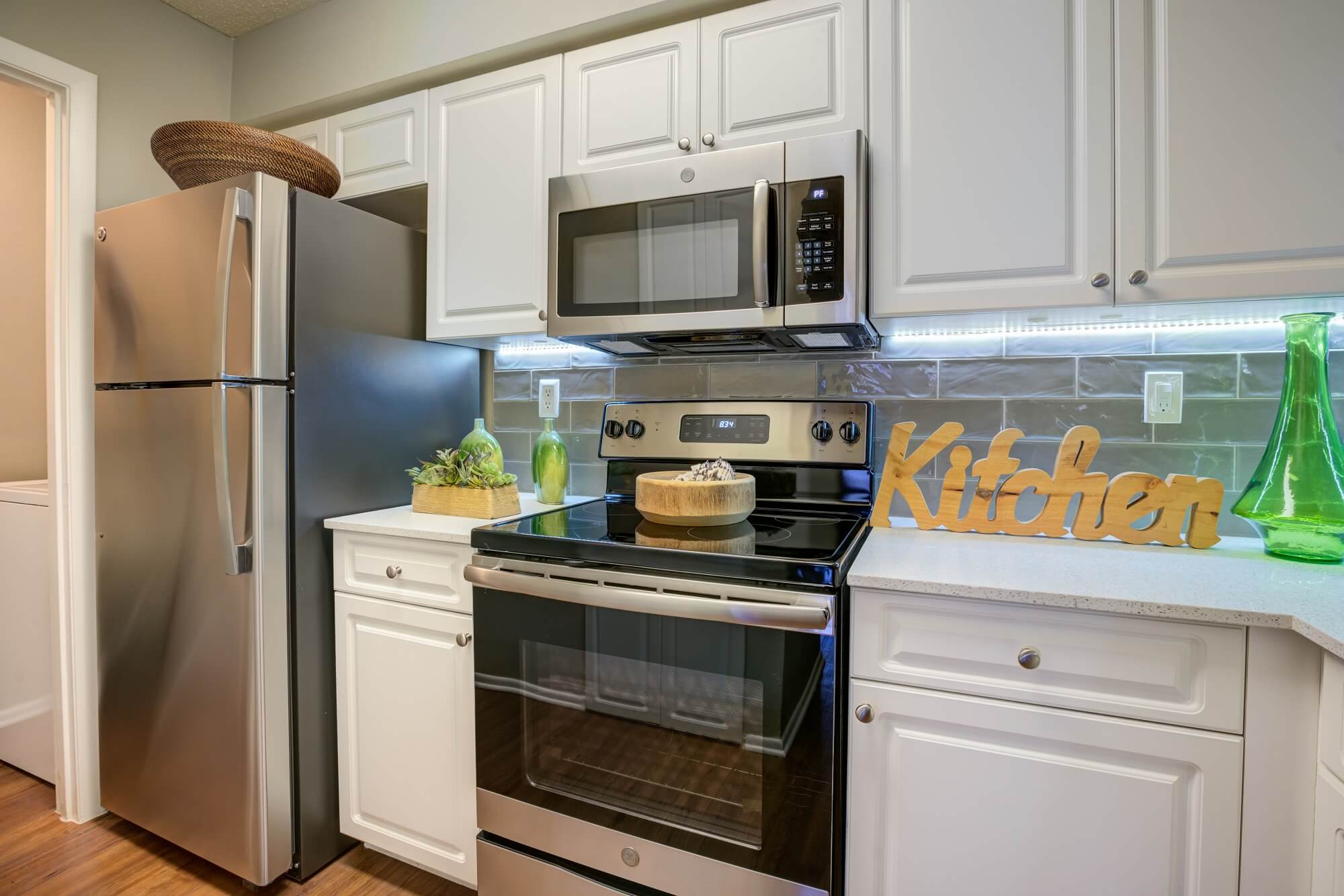 kitchen area with tile backsplash, stove, microwave, and fridge.