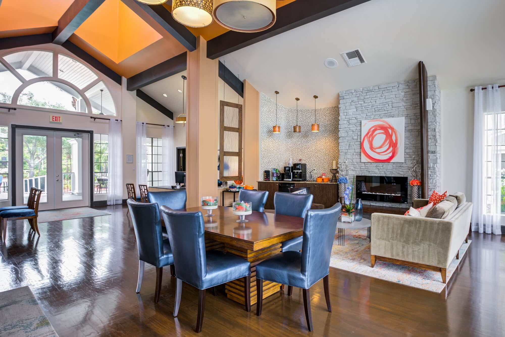 clubhouse view of decorative table, blue accent seating, fire place, and coffee bar.