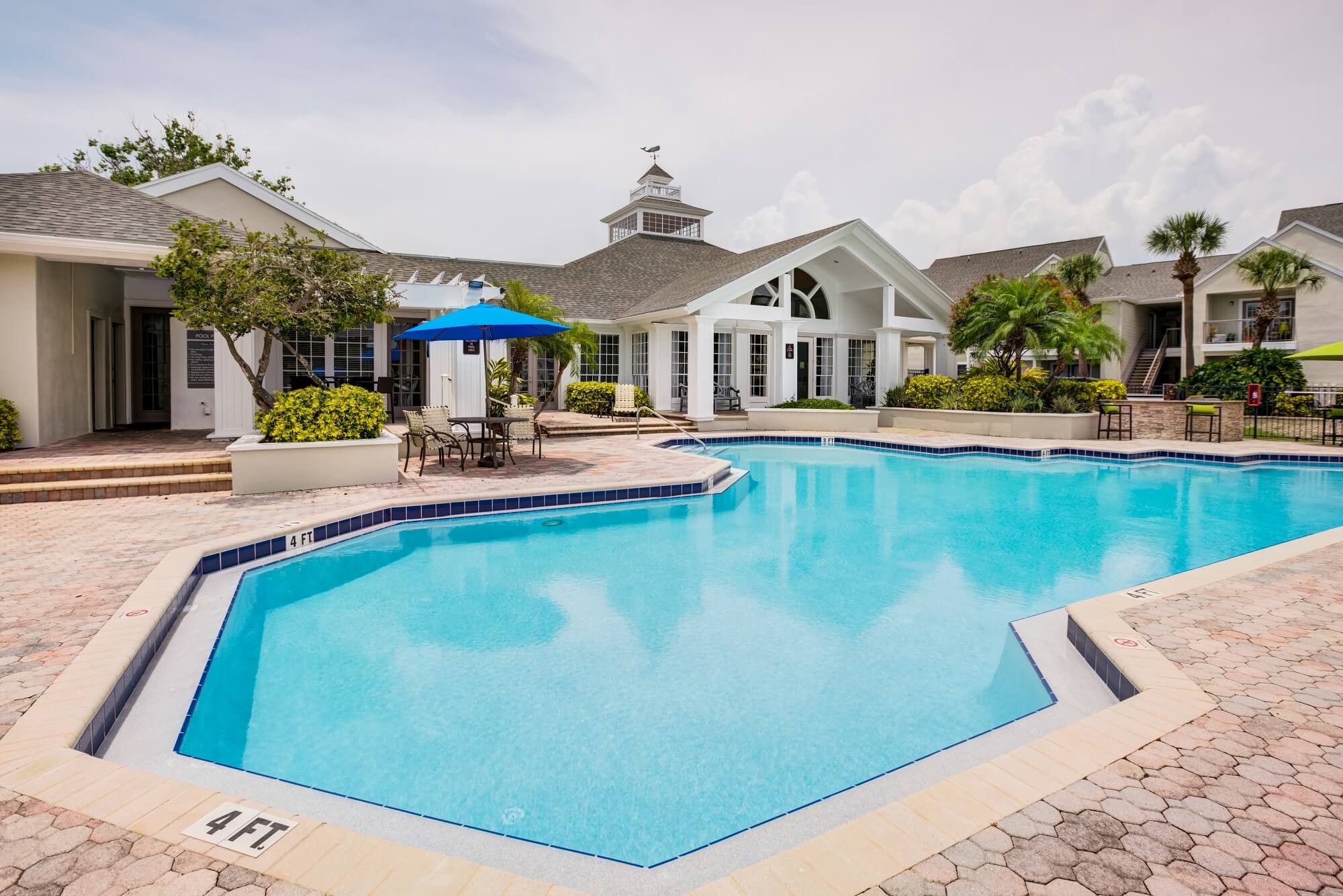 pool view with umbrellas, lounge chairs, and view of clubhouse.
