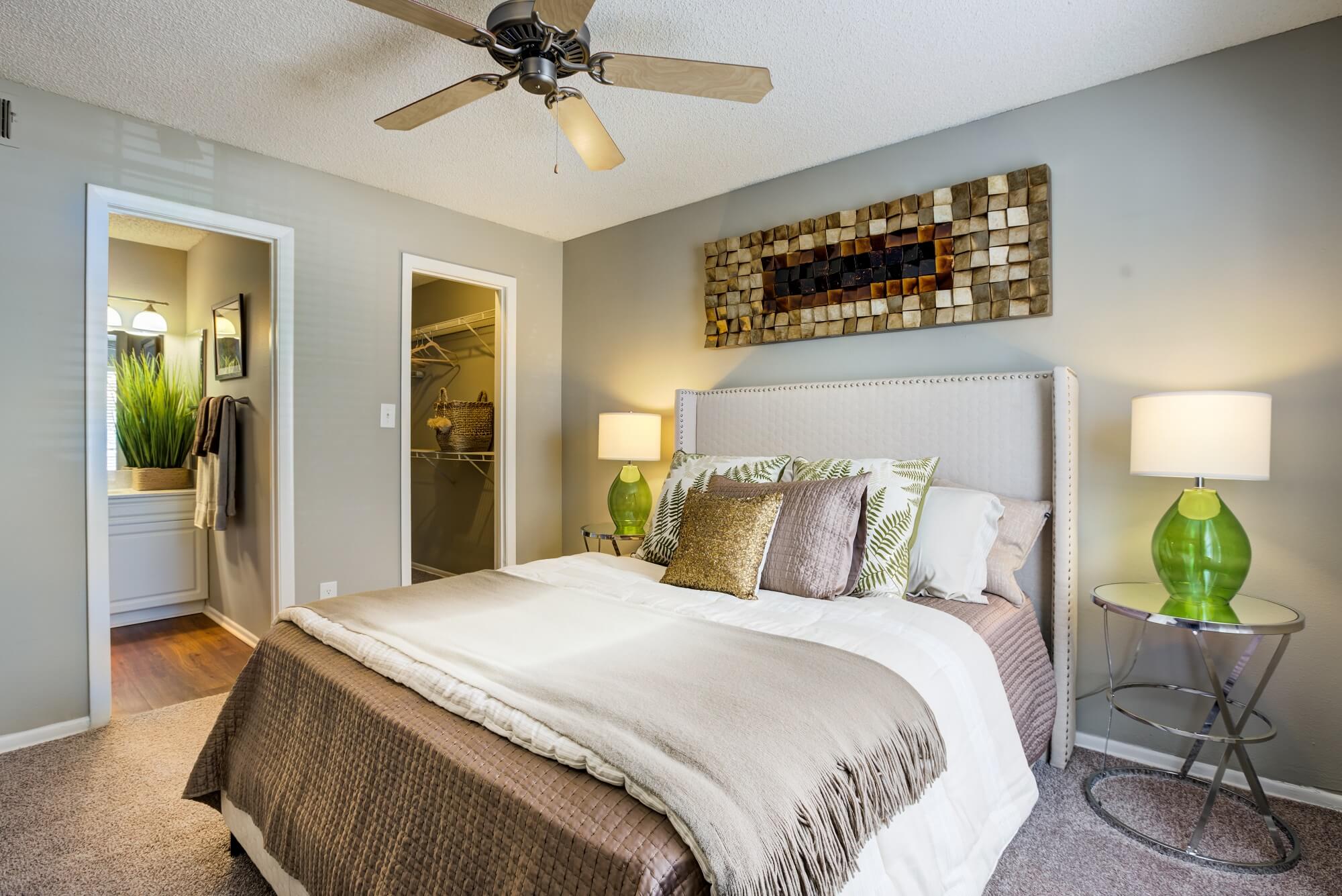 bedroom with ceiling fan, bed, decor, and view of closet and bathroom.